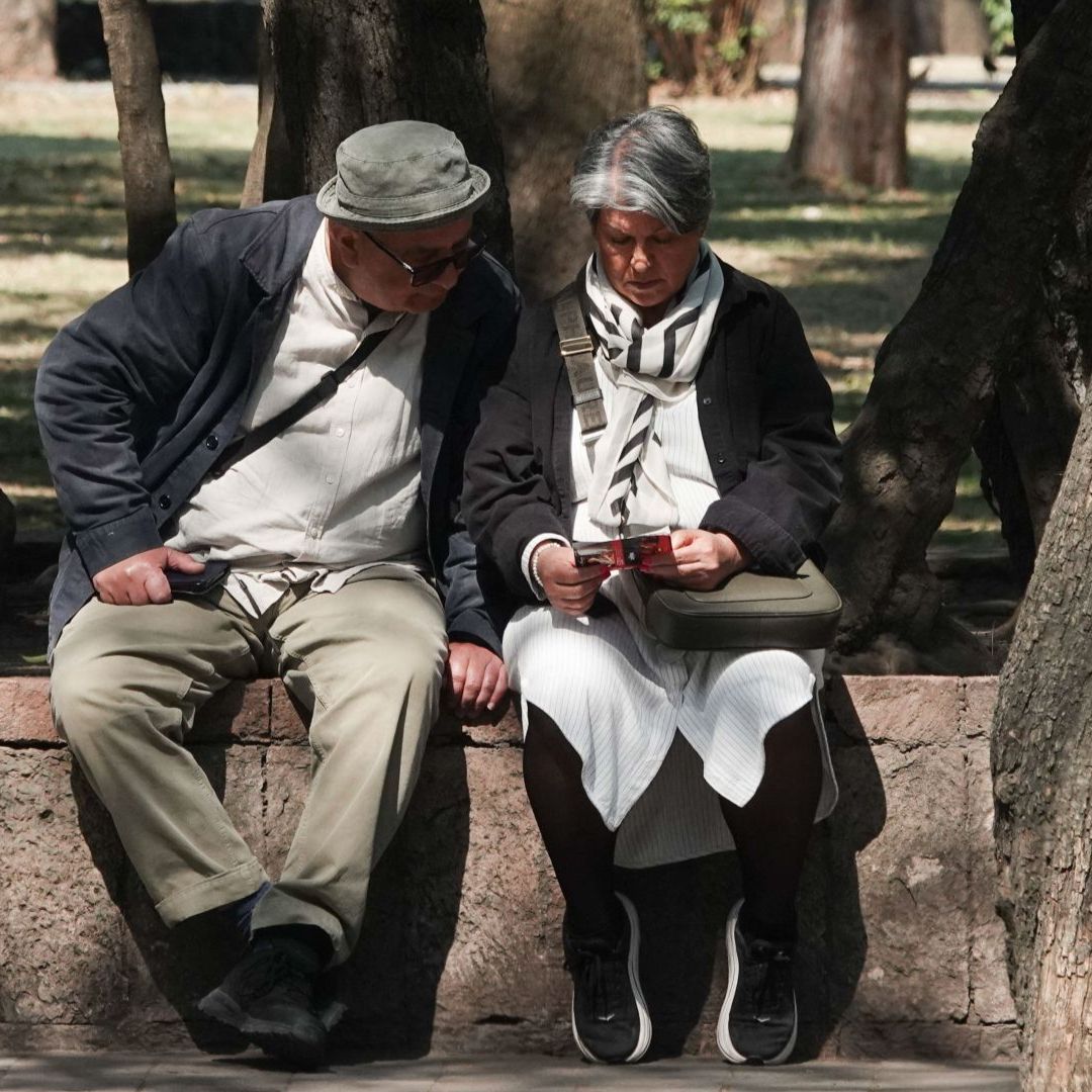 Adultos mayores sentados en un parque.